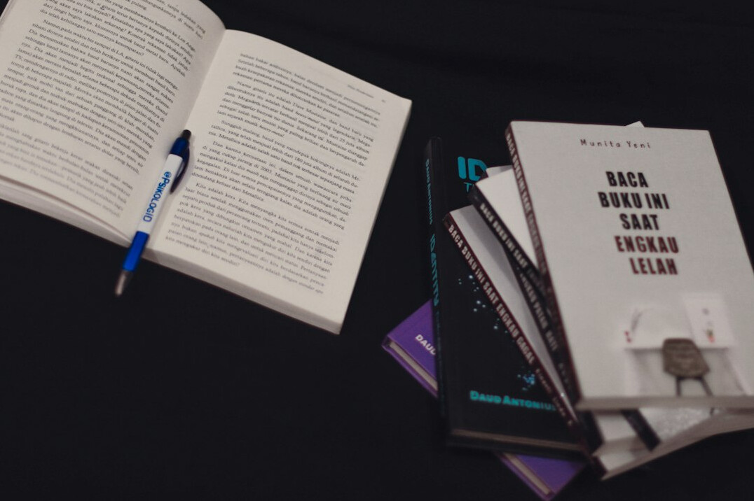 Notebook and pen next to a stack of printed articles